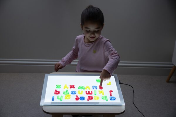 kind met letters op lichtbak